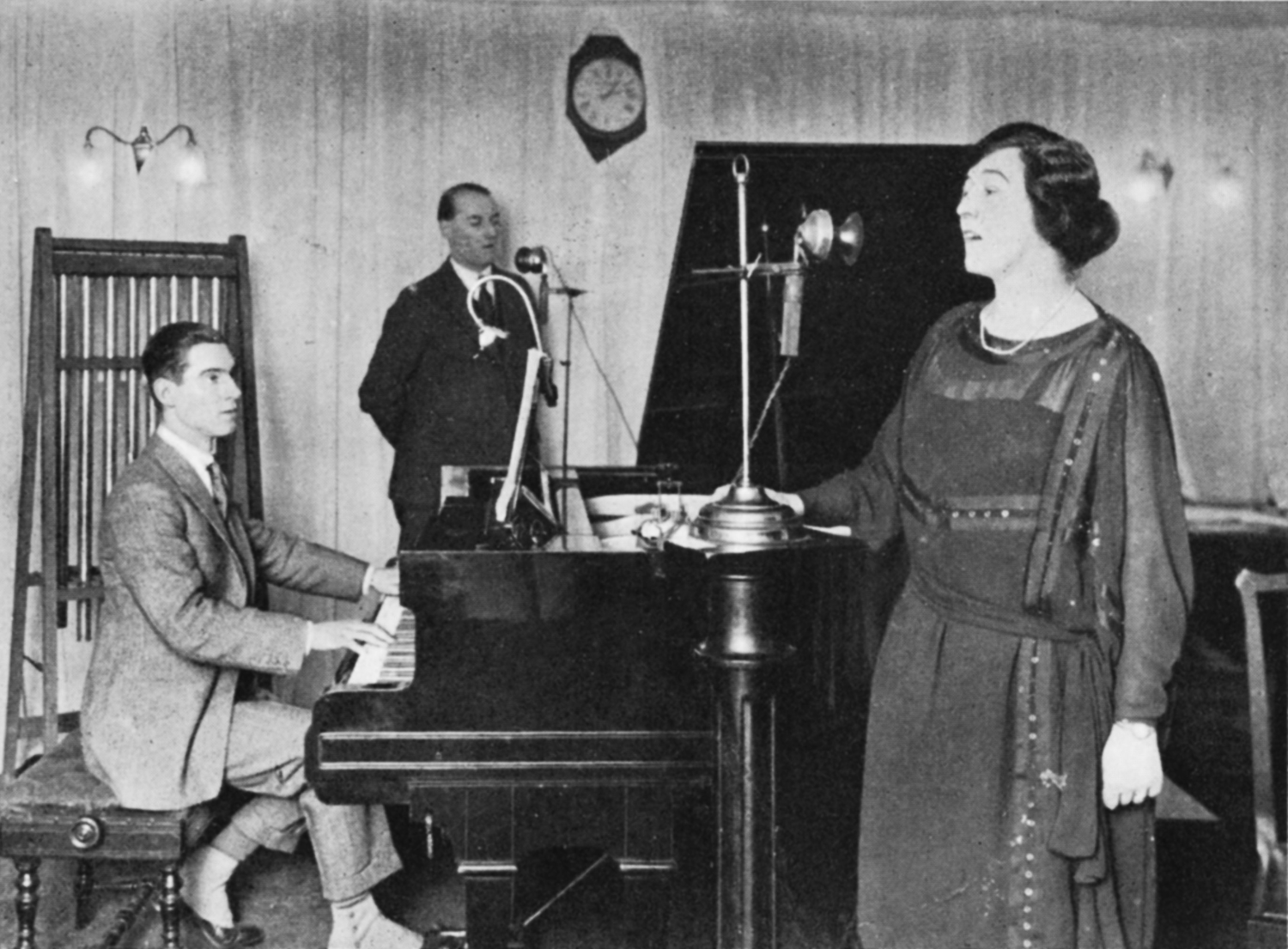 Man at a piano, man at a microphone, woman sings into a microphone
