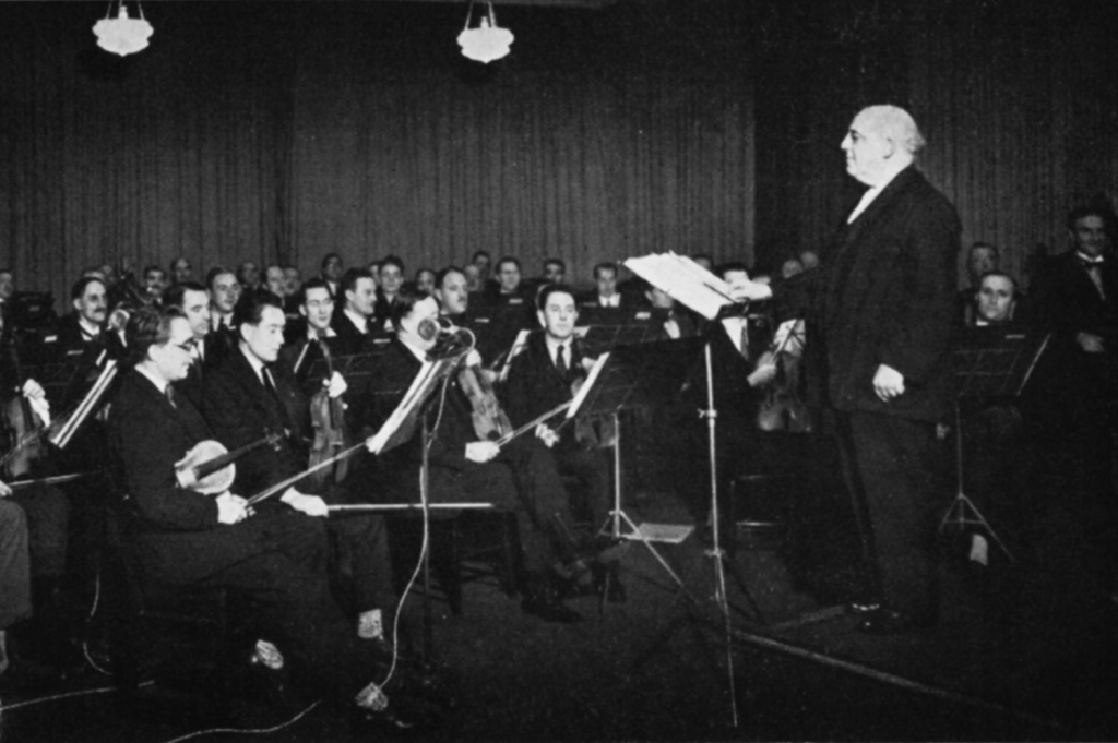 A conductor stands in front of an orchestra