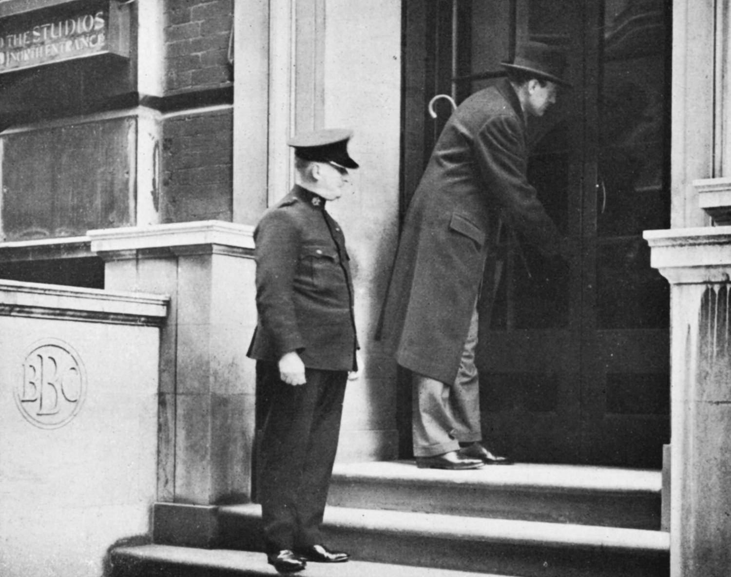 A commissionaire watches a man lock a big door