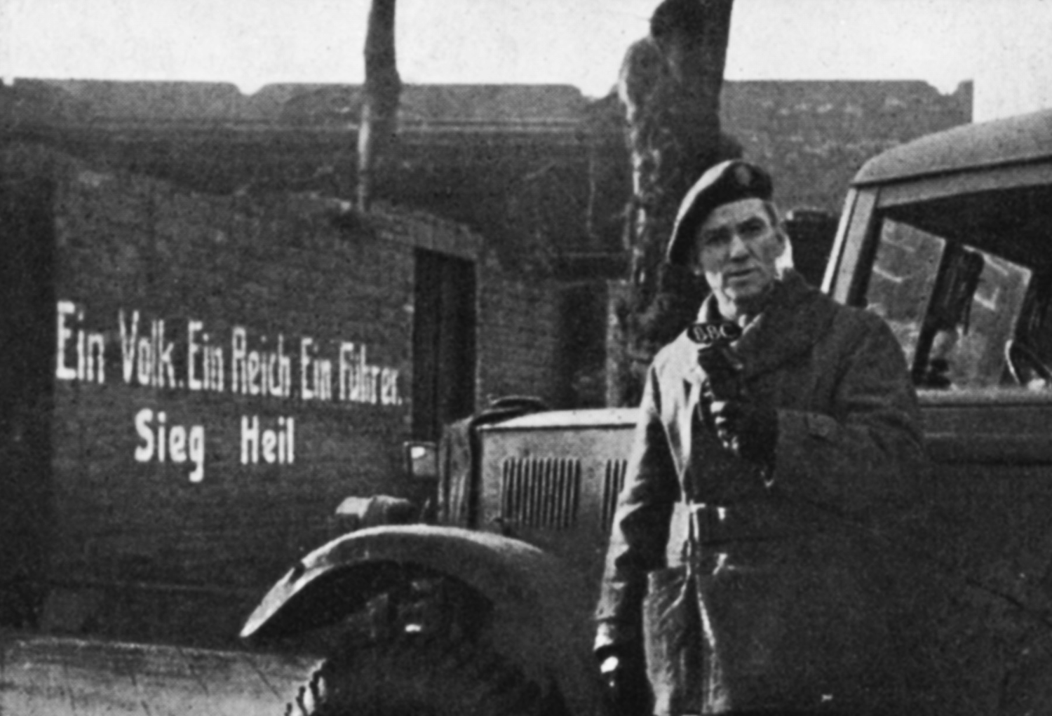 A man stands in front of a wall with Nazi slogans written on it